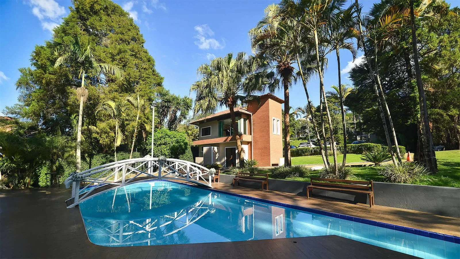 Jardim e piscina do Alpes Serrano, com ponte e áreas verdes na Serra da Cantareira